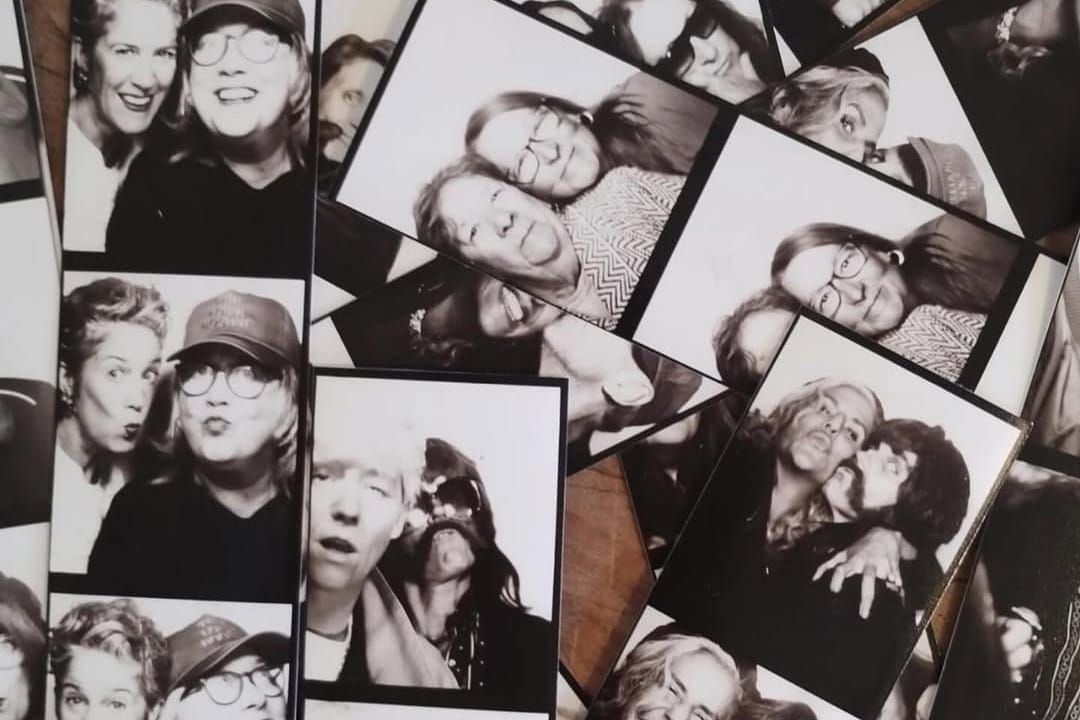 A pile of black and white photobooth photographs each featuring two people.