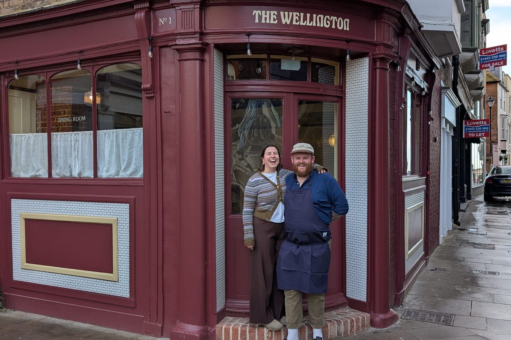 A man and a woman stand outside a pub
