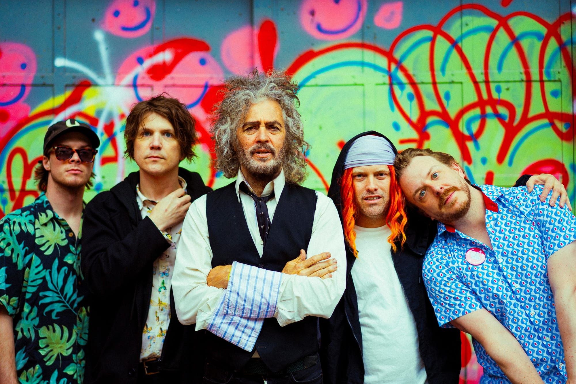 Five men stand in front of graffiti