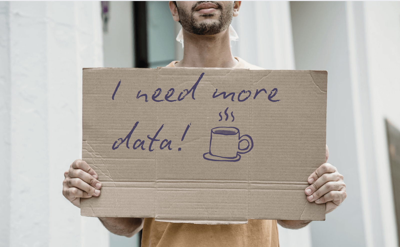 Man holding a sign that reads: "I need more data"