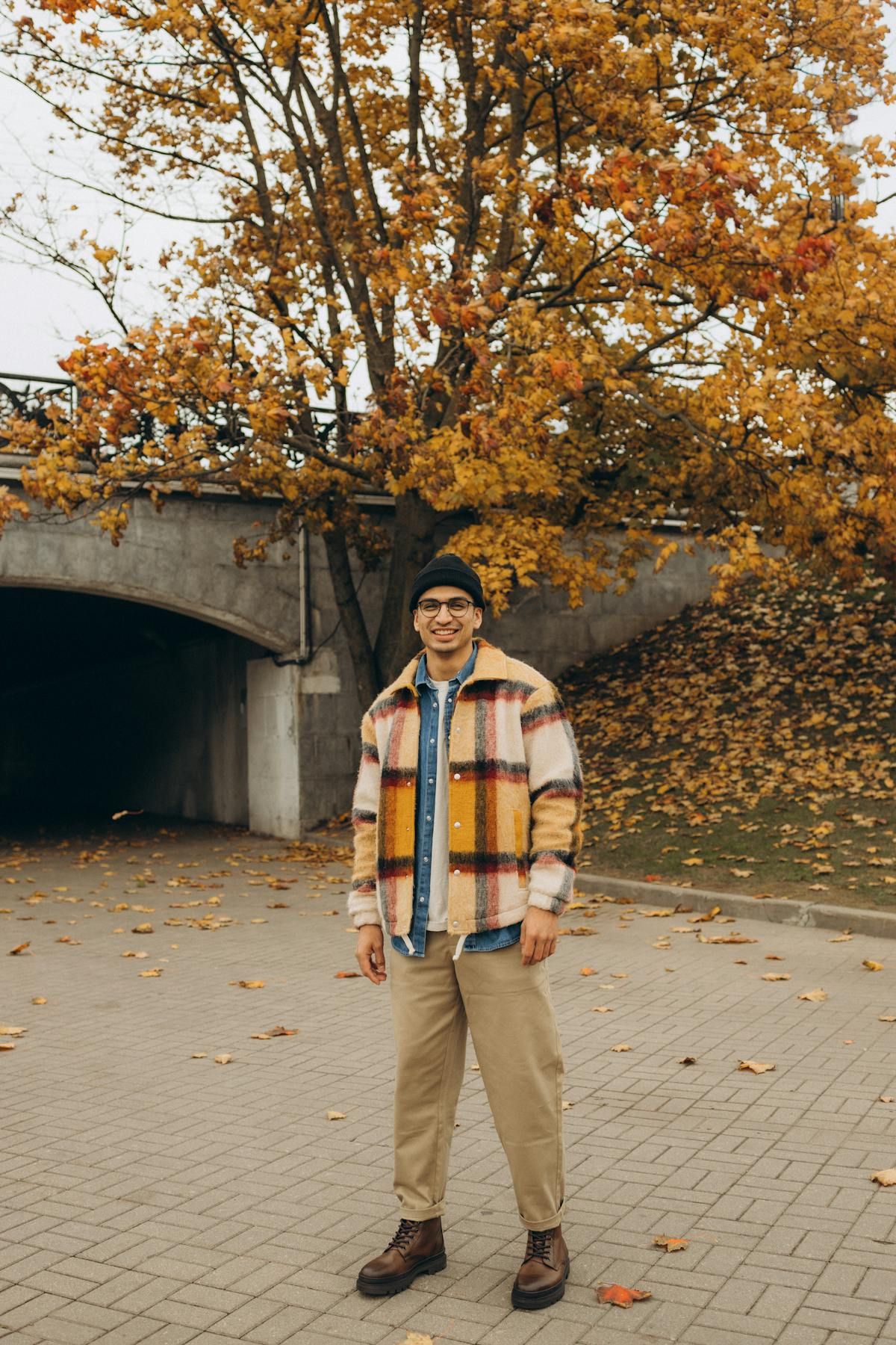 Man in plaid shirt jacket and beanie walking through an autumn park, the layered look for 58 degree weather