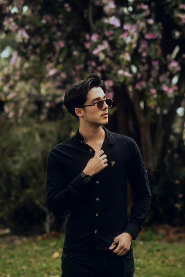 Young man in a single long sleeve button-down outdoors with spring blossoms, the comfortable single layer for 68 degree weather