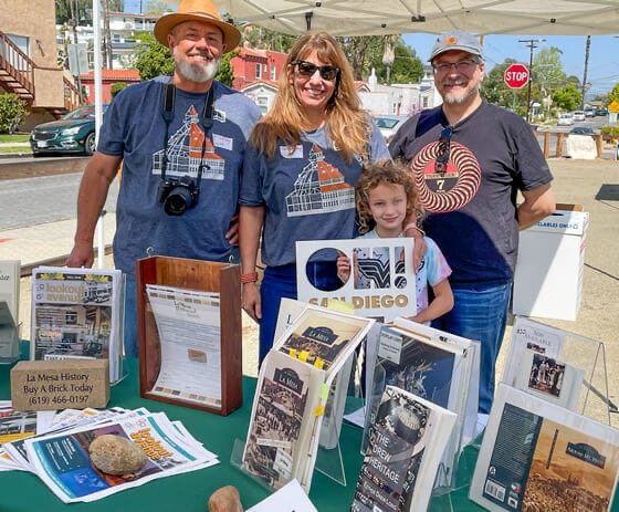 La Mesa History Center volunteers, three adults and one child, stood behind a table of books and leaflets at the McKinney House Museum