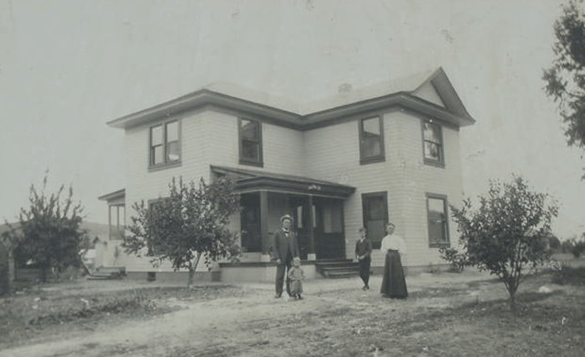 Black and white photo of exterior of early twentieth century house in La Mesa with two adults and two children
