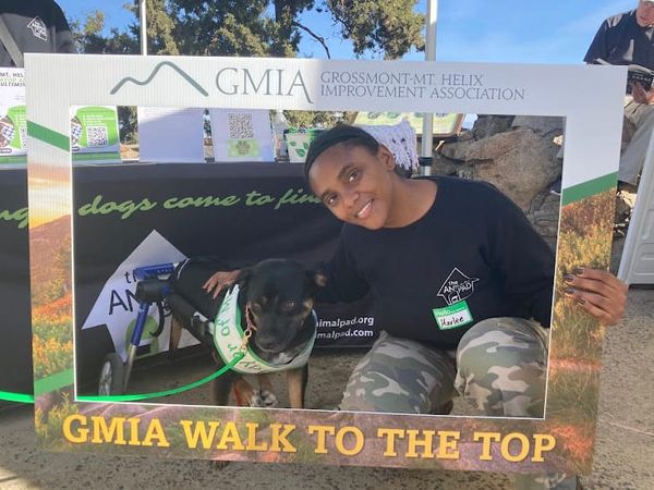 Woman with dog and sign that reads GMIA Walk to the Top