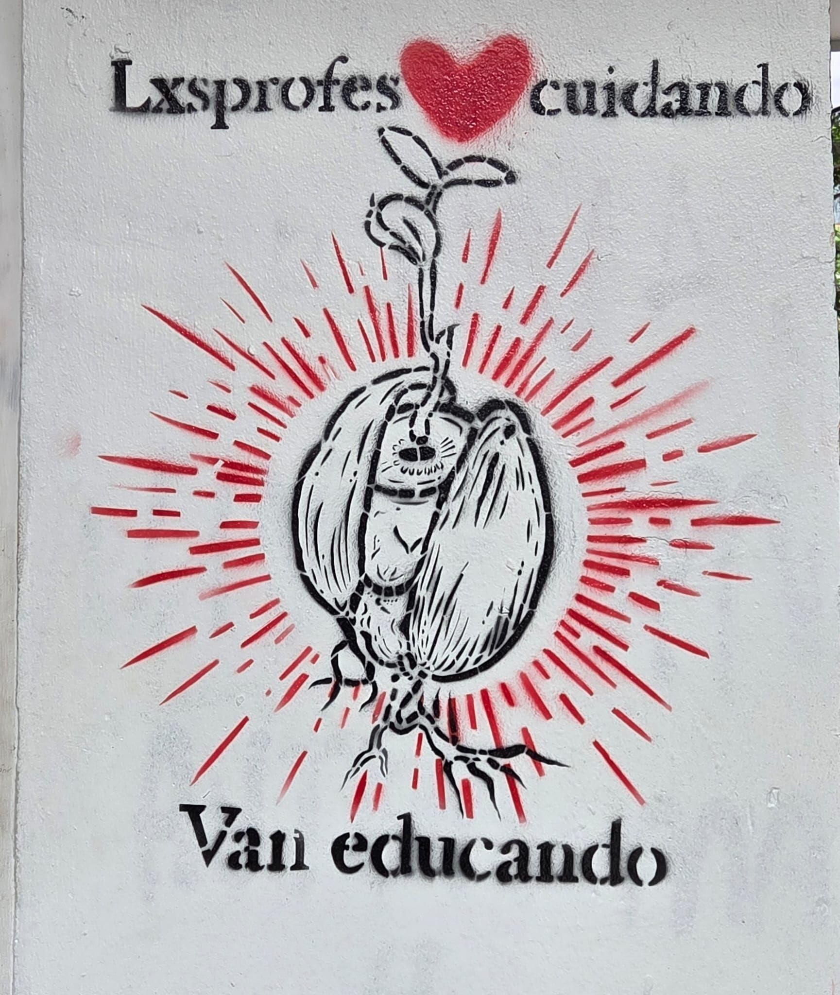 Imagen de un mural hecho de un stencil con un dibujo de una semila floreciendo y el texto "lxs profes cuidando, van educando".