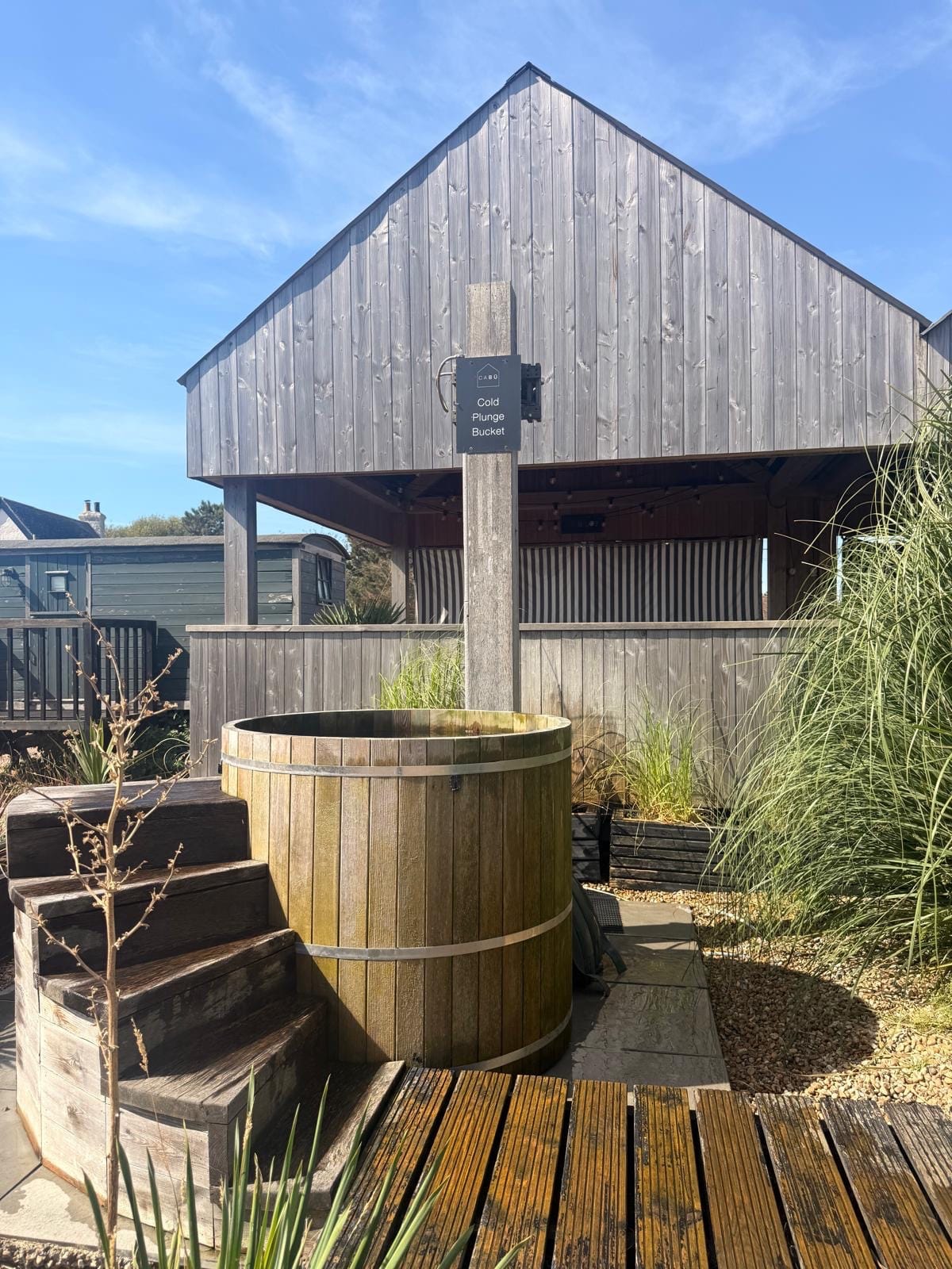 Oak cold plunge bucket with steps beside the barrel sauna at Cabu by the Sea, Dymchurch