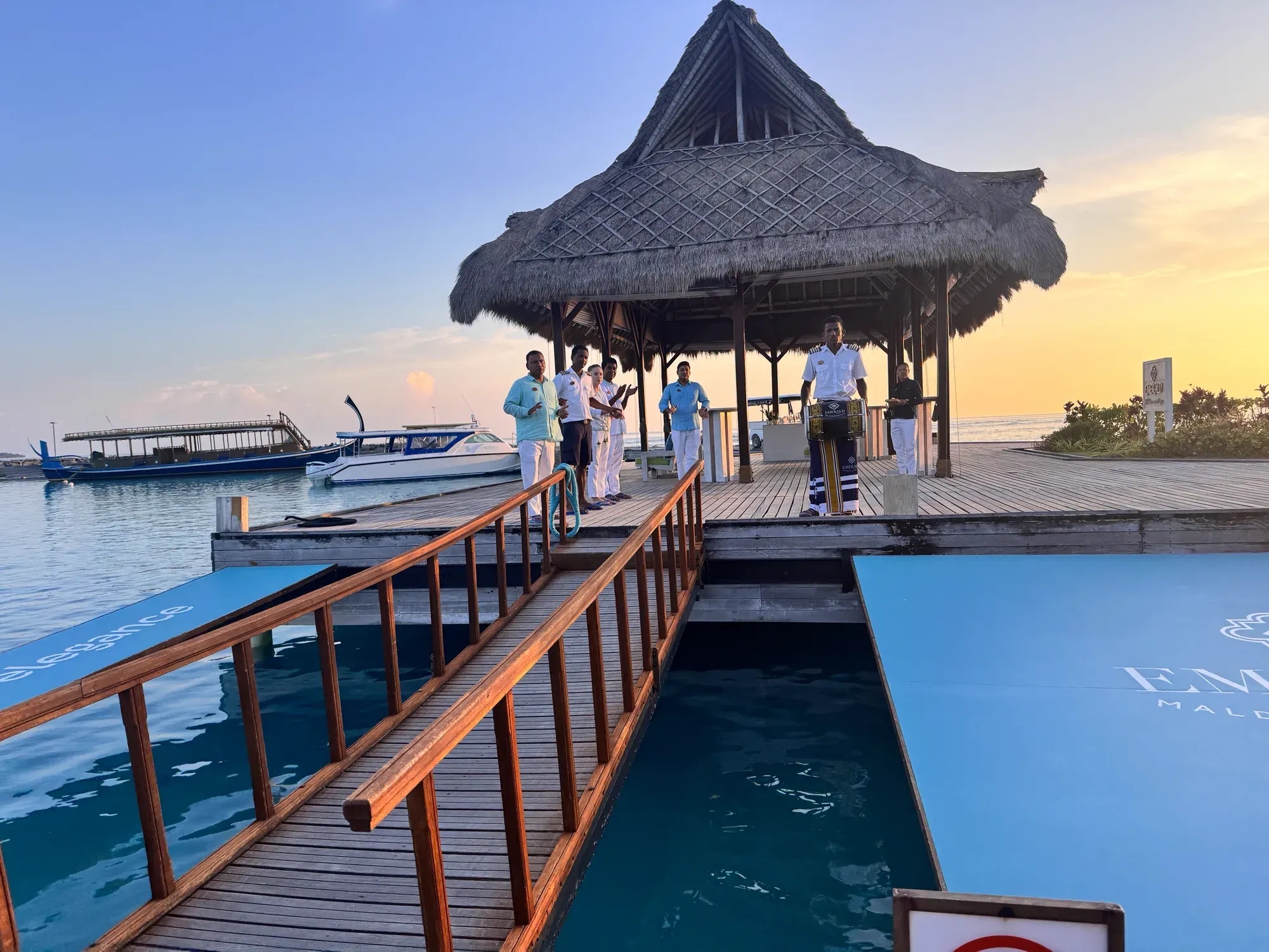 Thatched arrival jetty pavilion and speedboats at sunset at Emerald Maldives