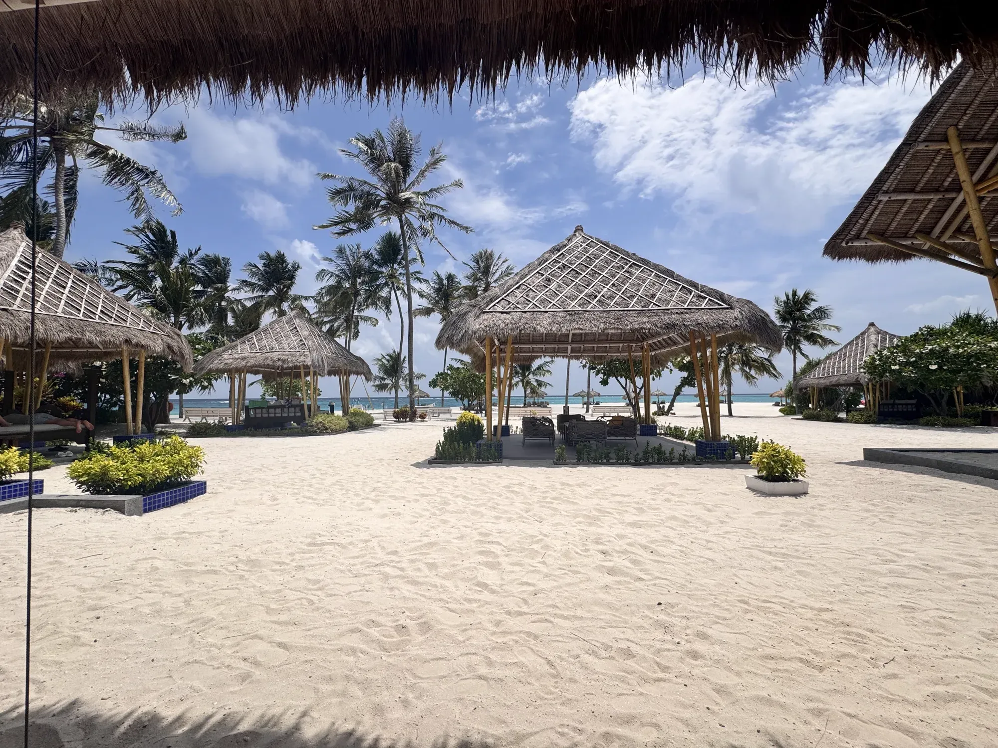 Thatched Beach Club Grill cabanas on white sand at Emerald Maldives