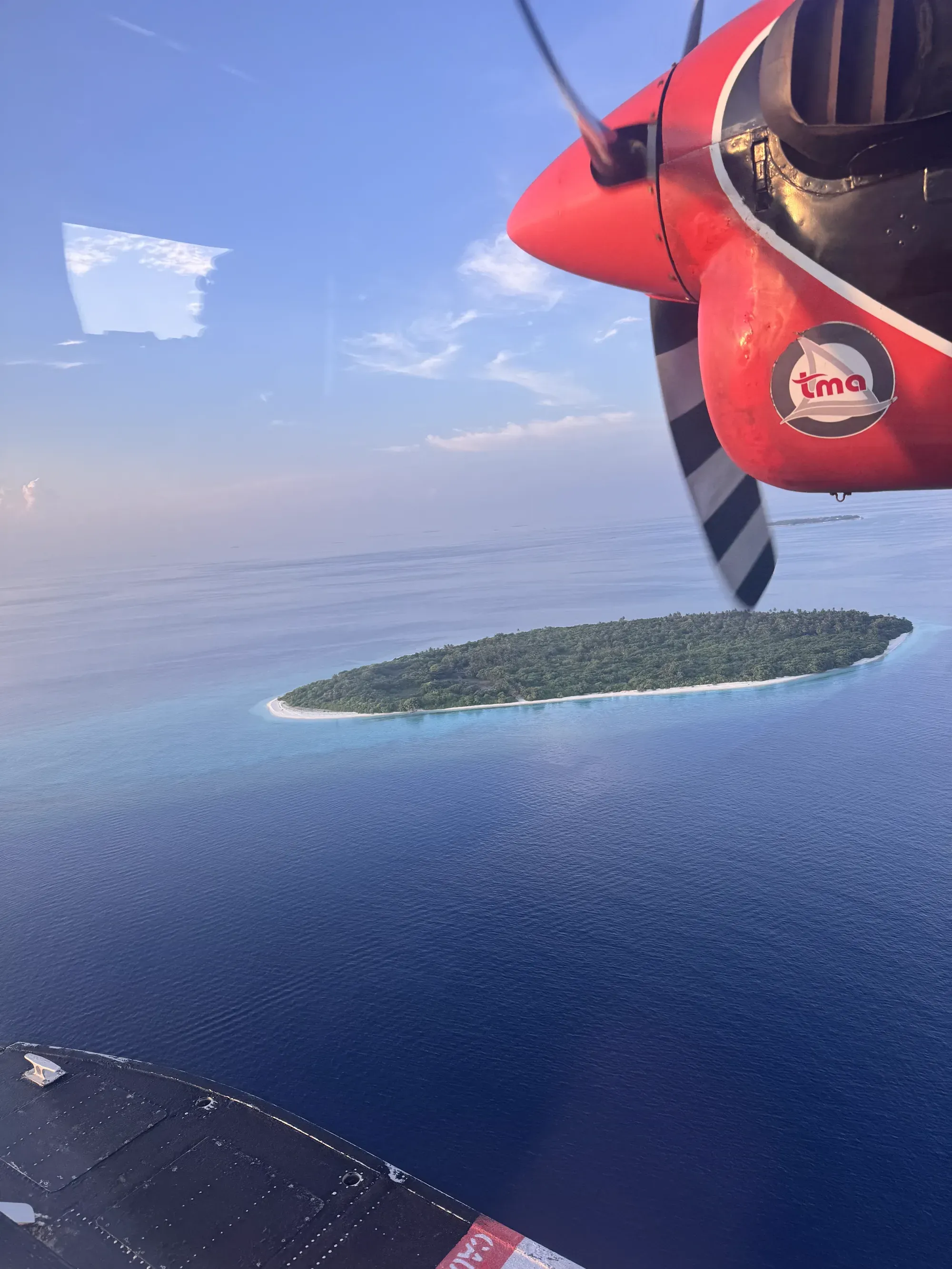 Seaplane propeller and wing above a small Maldivian island on approach