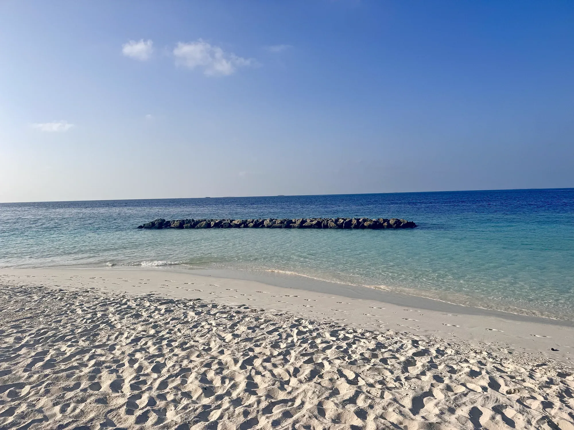 White sand beach and clear turquoise water over the house reef at Emerald Maldives