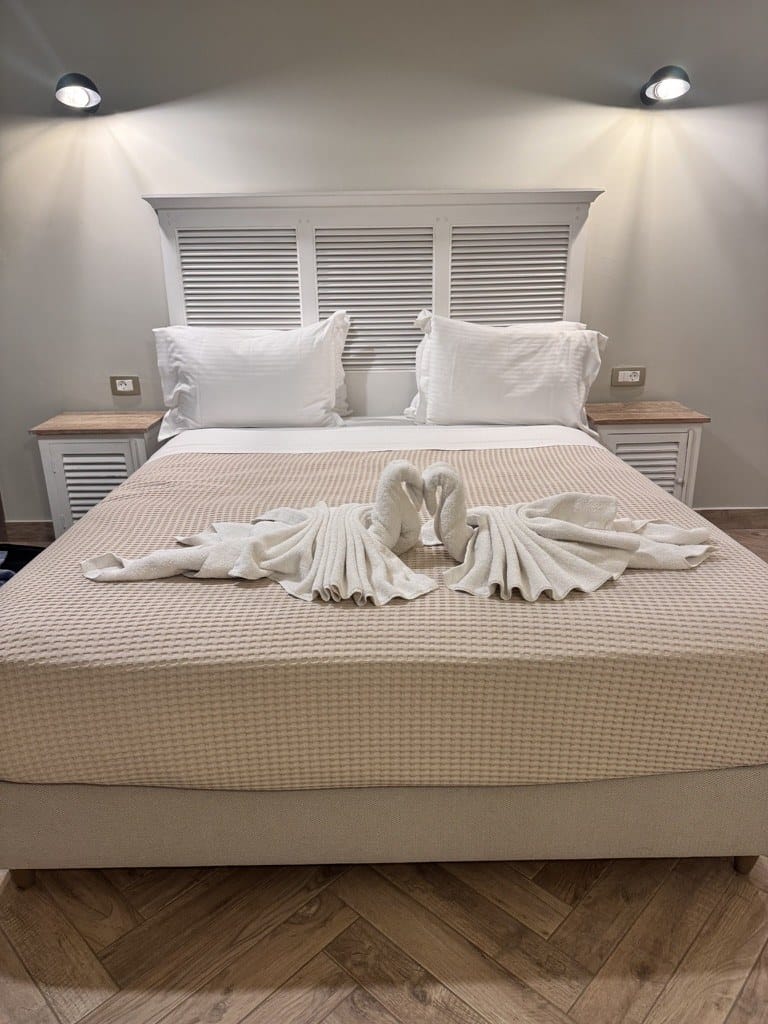 Made bed with towel swans and white linens at La Signora Hotel, Kefalonia