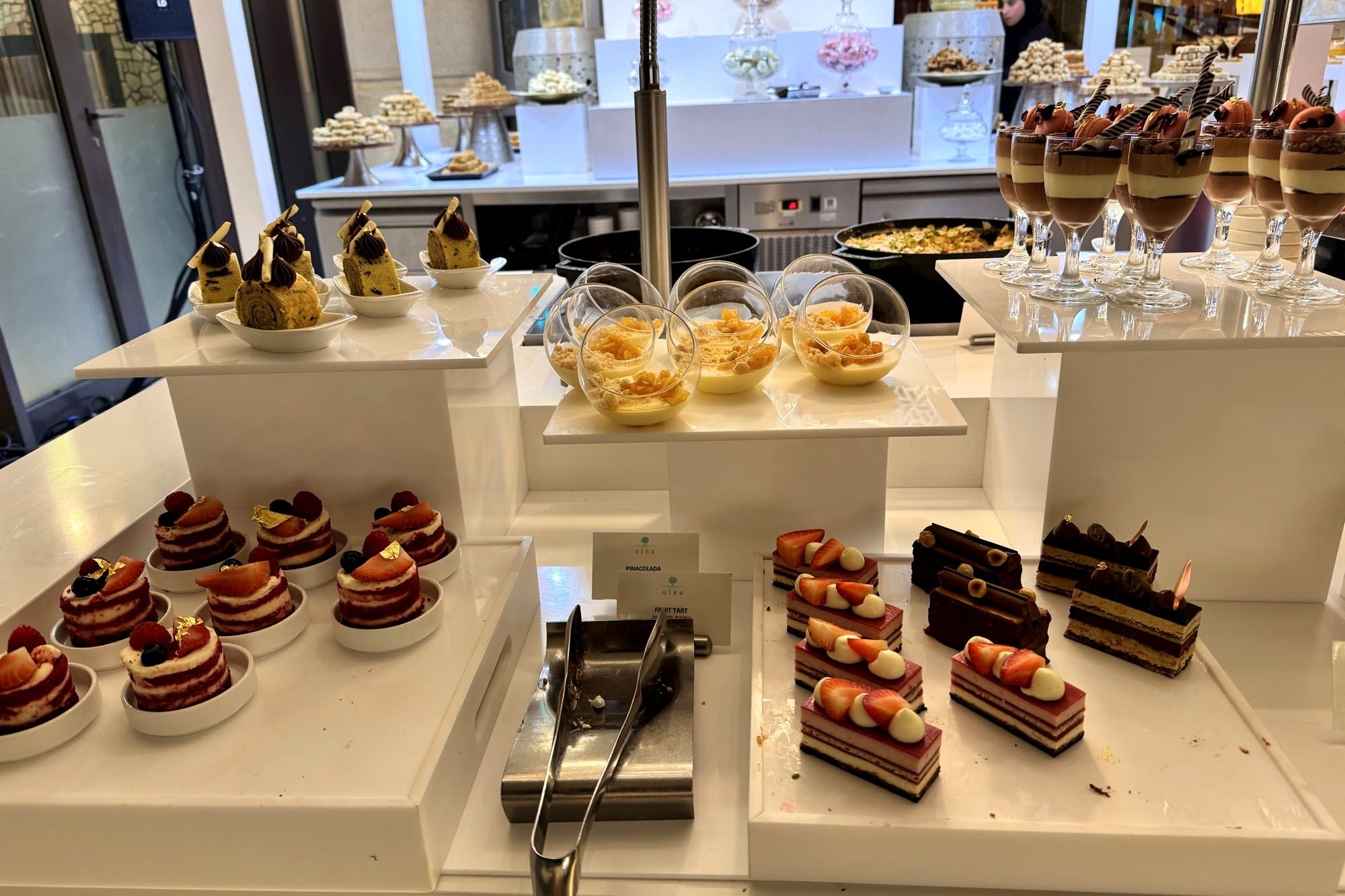 Buffet dessert counter with layered cakes, tarts and chocolate mousse glasses