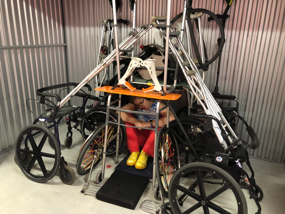 Brennan sits underneath a tower of mobility devices.