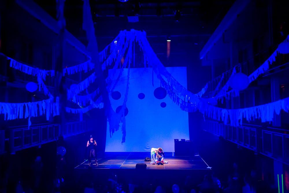 Artist Yousef performing on a stage with a Deaf ASL interpreter at the side of the stage.