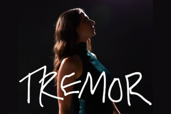 Brianna stands in profile wearing a green dress. "TREMOR" is written across the photo in white.