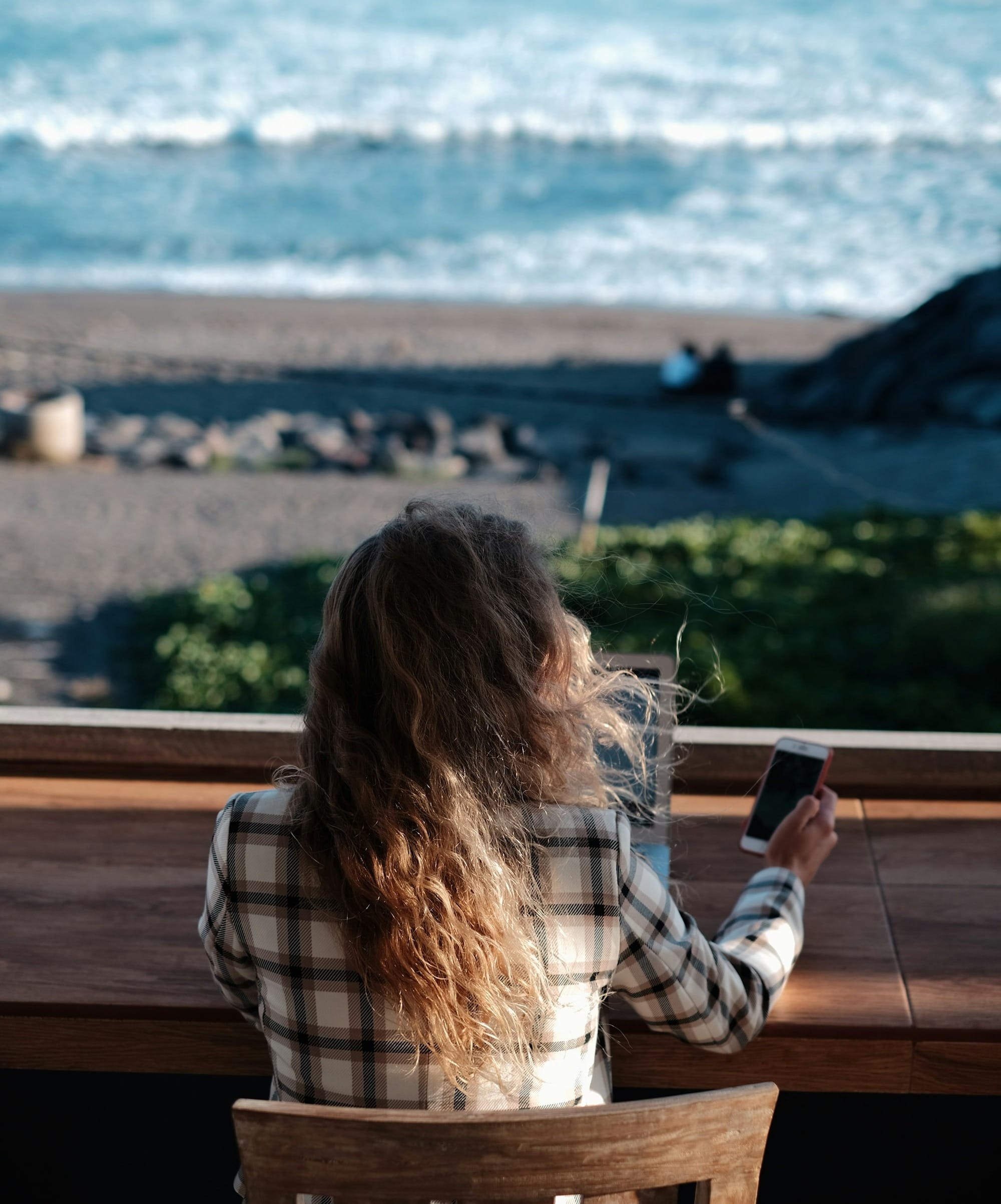 woman in white and black plaid shirt holding black smartphone