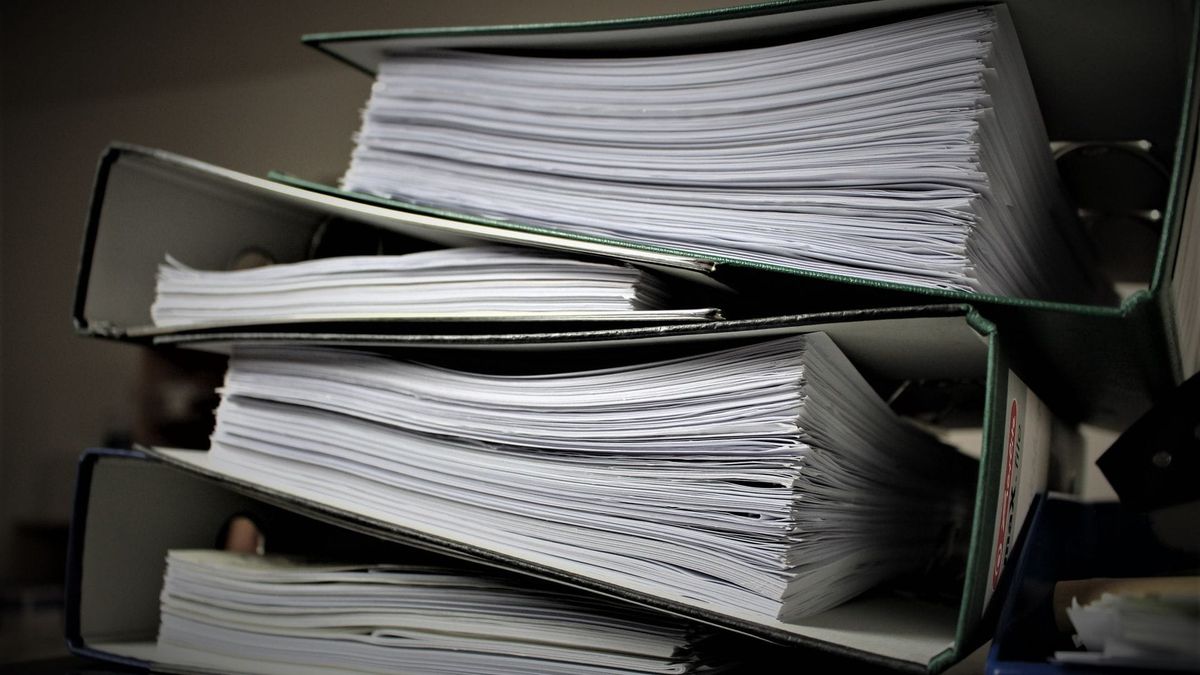 A stack of paper-filled folders on a shelf.