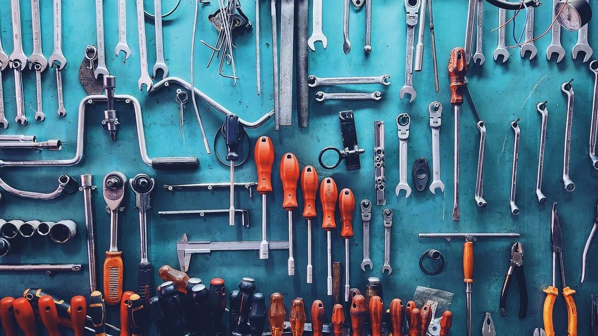 A wall of sorted hand tools hanging above a workbench.