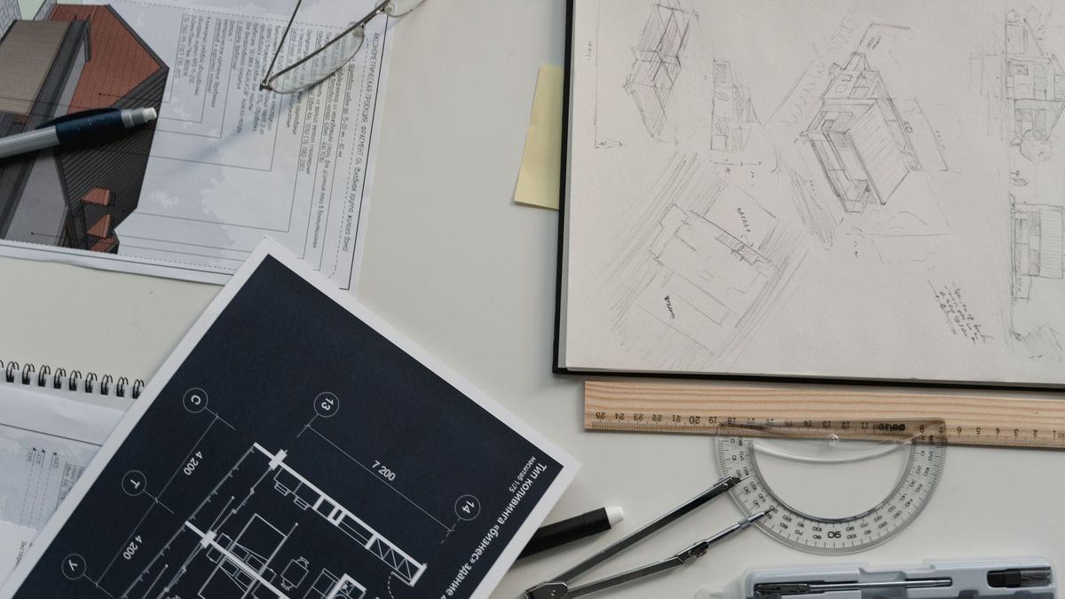 Architectural sketches, blueprints, and drafting tools spread across a desk.