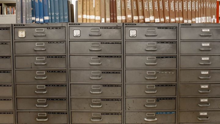 Rows of gray metal file cabinet drawers with books lined along the top.