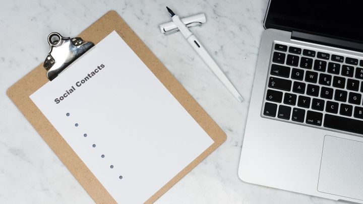 A clipboard with a short checklist sits beside a laptop and pen on a desk.