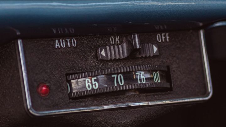 A close-up of a vintage dashboard control panel with labeled switches, dials, and a red indicator light.