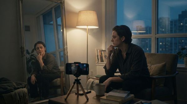 A phone screen showing a social media interface, subject partially visible, blurred background, warm light.