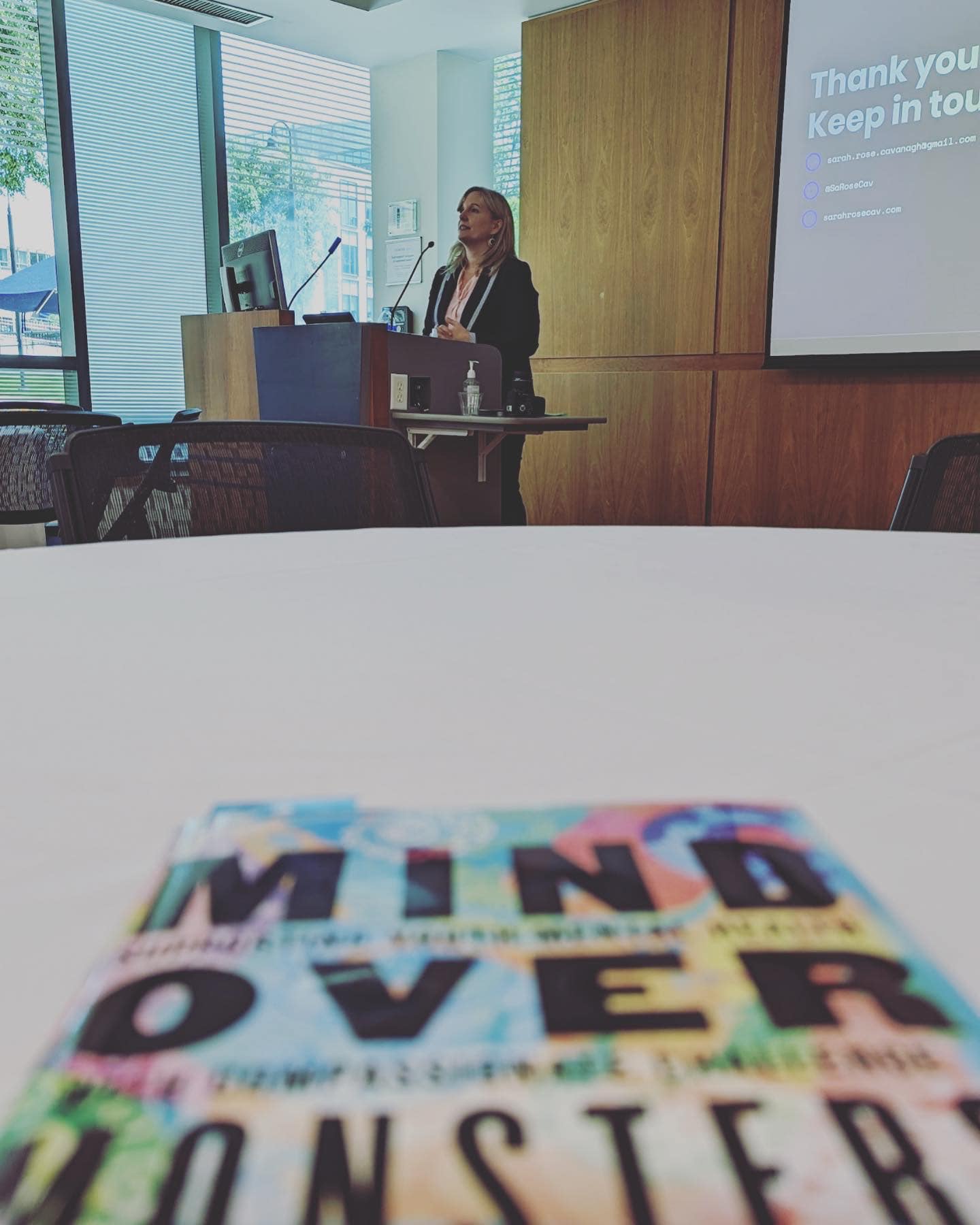 Author reading at podium with blurry book in foreground