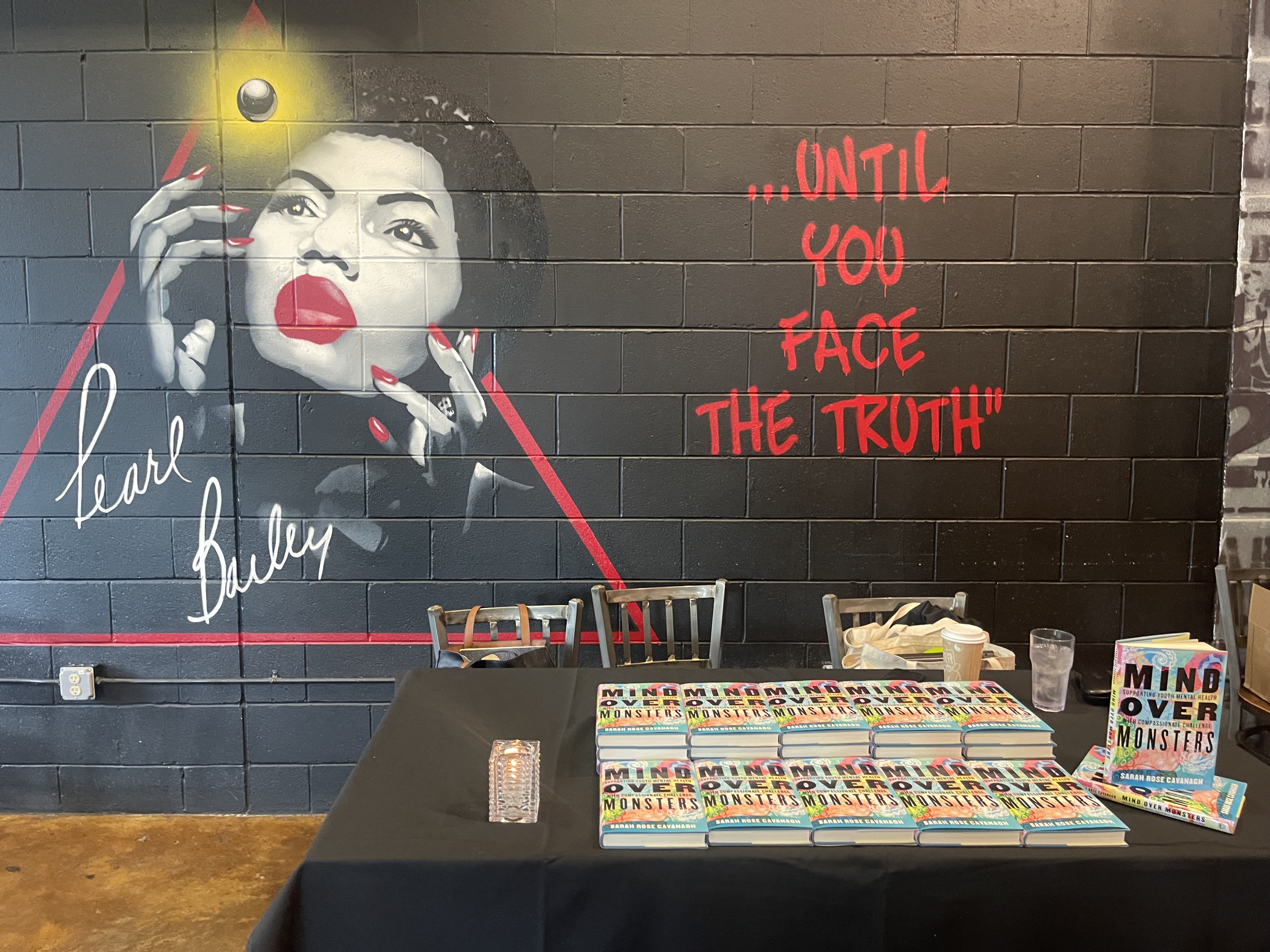 Pile of Mind Over Monsters books in front of a wall painting of Pearl Bailey.