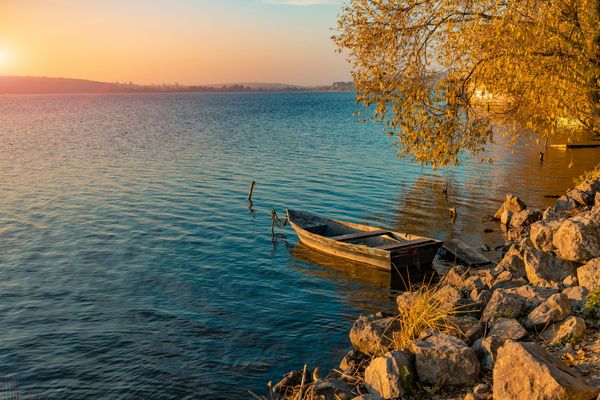 A rowboat is tethered in a lake at sunset
