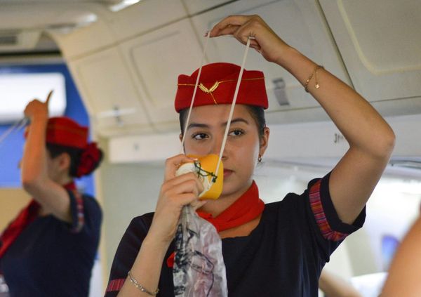 an air stewardess demonstrates how to put on an emergency oxygen mask on a plane, in case of emergency.