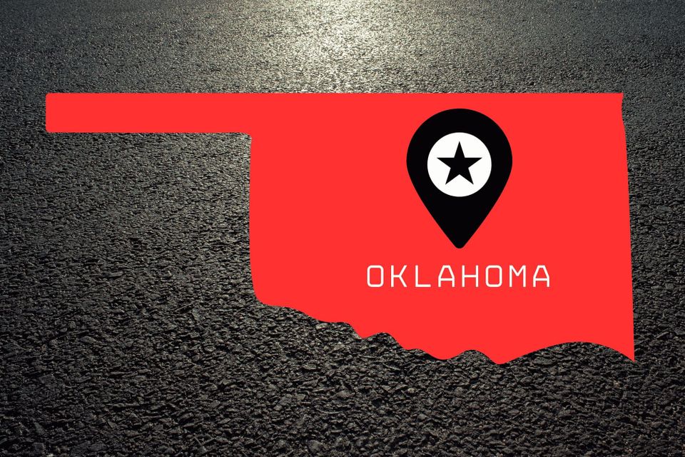 A red rendering of the outline of Oklahoma over asphalt
