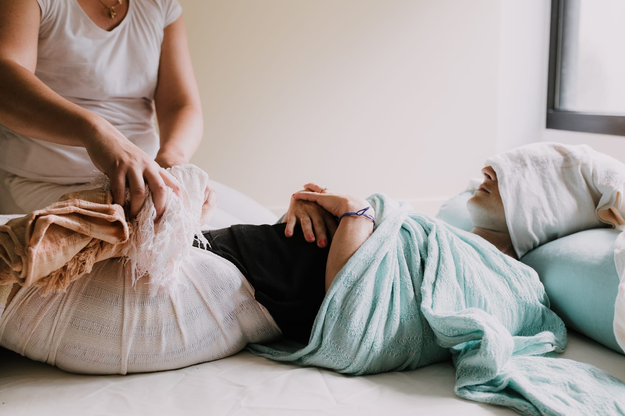 Massage Rebozo prénatal réalisé avec des tissus enveloppants, future maman allongée dans une ambiance calme et bienveillante
