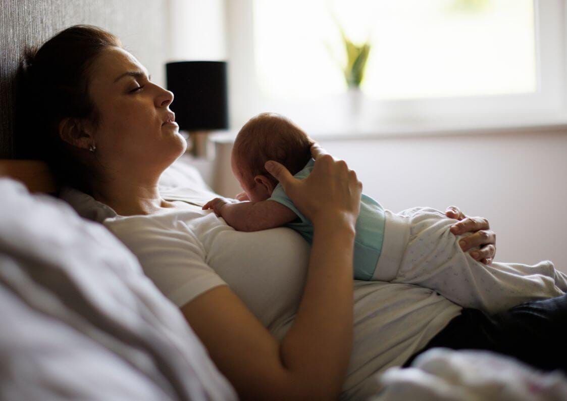 Baby blues après accouchementJeune mère allongée avec son bébé sur la poitrine pendant le post-partum, moment de lien et de réconfort à la maison