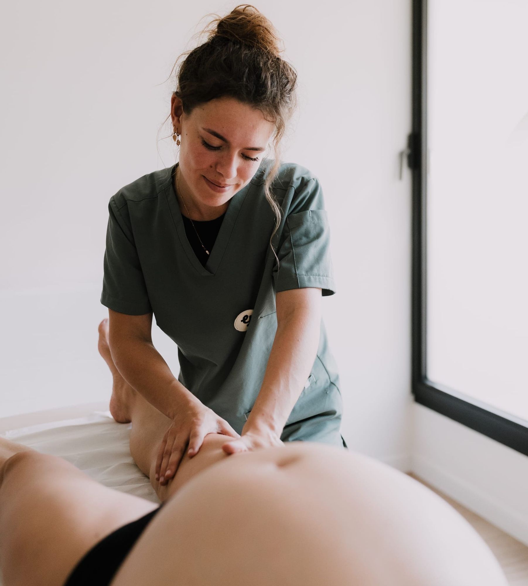Drainage lymphatique réalisé par une praticienne sur les jambes d’une femme enceinte, massage doux et bien-être prénatal.">