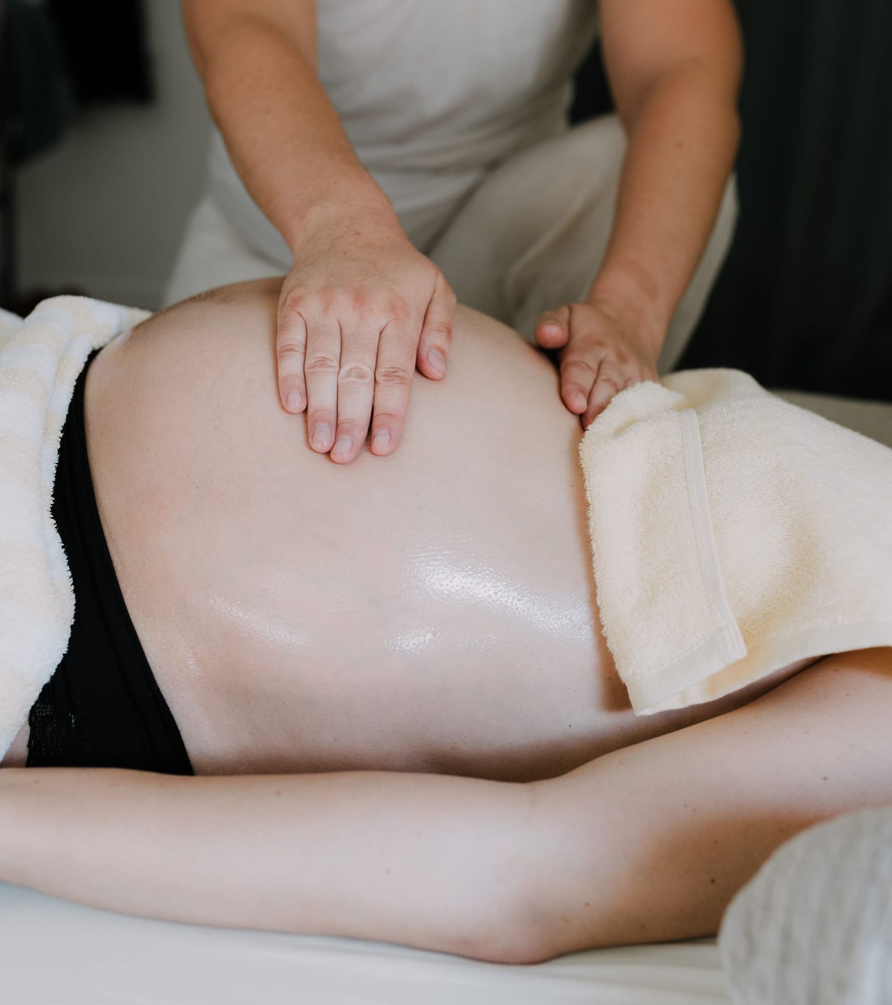 Massage prénatal sur le ventre d'une femme enceinte allongée, moment de bien-être et de détente