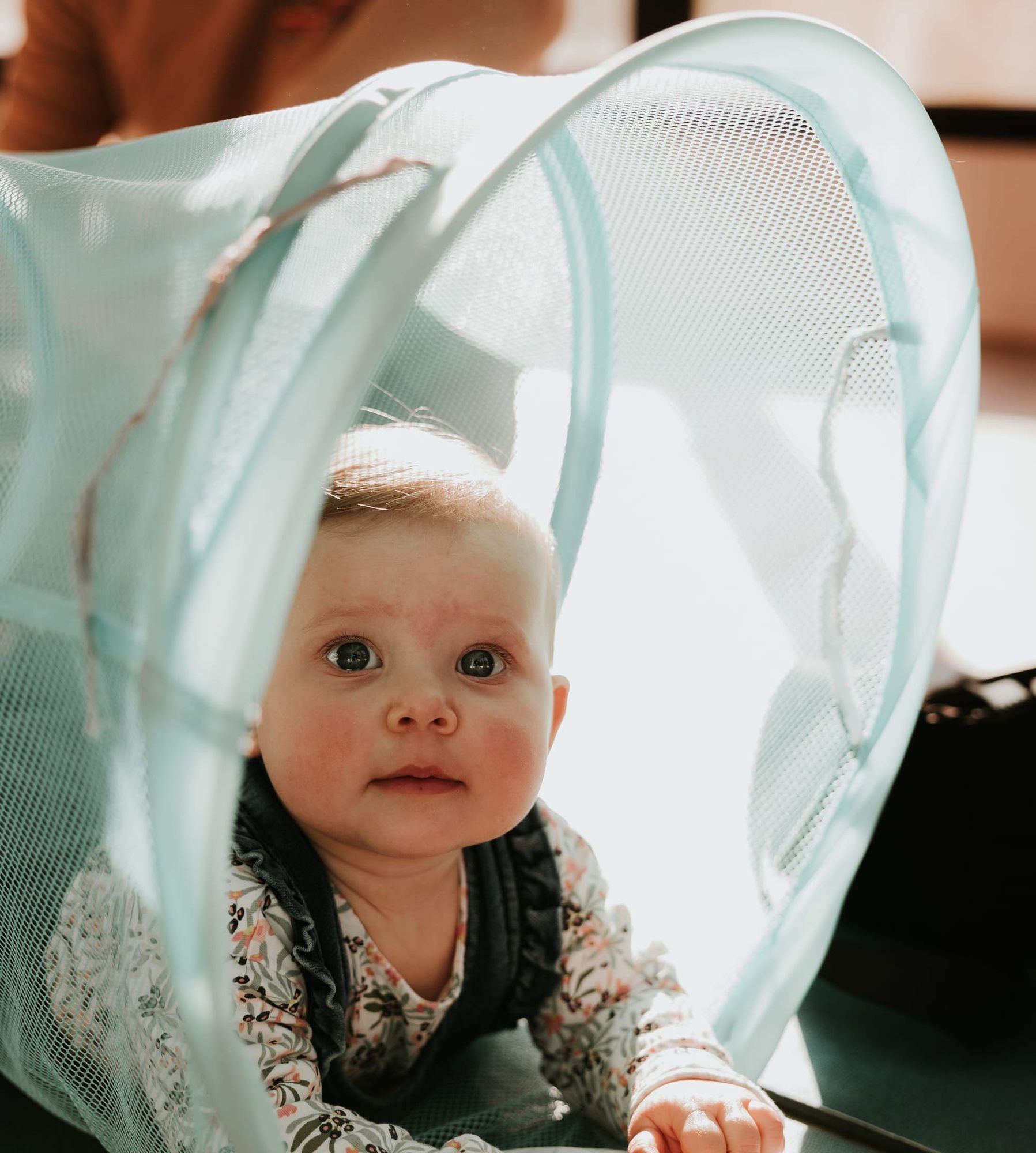 Bébé en pleine exploration motrice, regardant avec curiosité sous un tunnel sensoriel lors d’un atelier de motricité libre