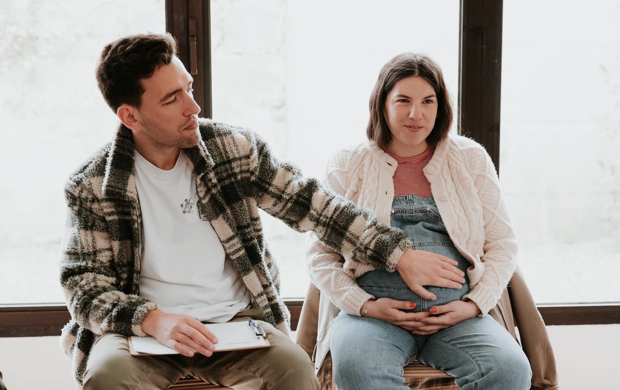 Un futur père pose sa main sur le ventre de sa partenaire enceinte pendant un atelier de préparation à la parentalité