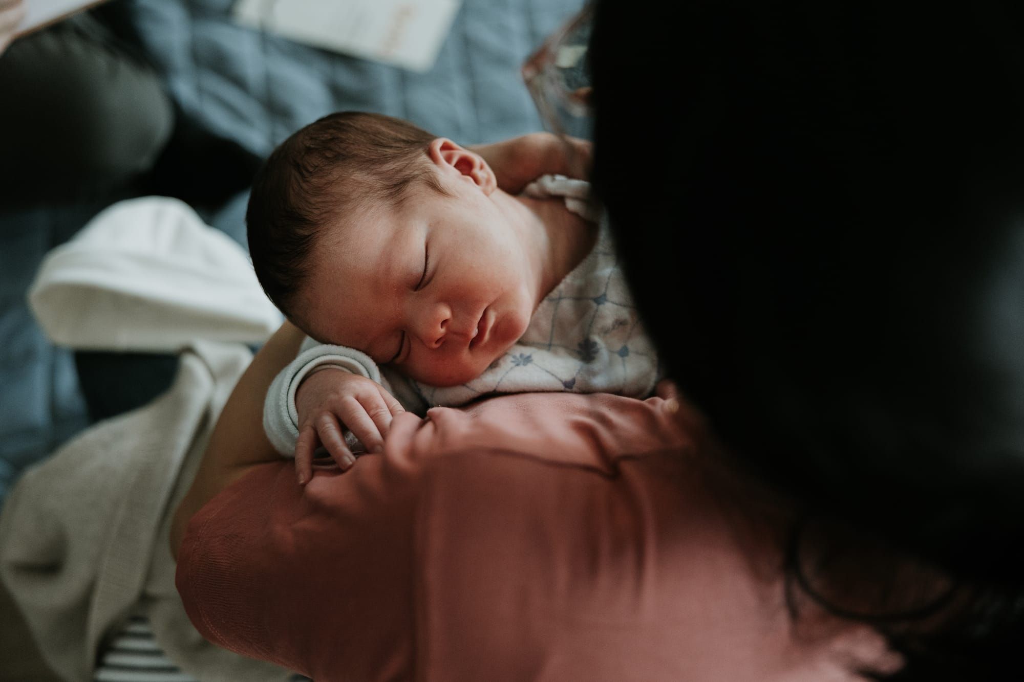 Bébé endormi paisiblement dans les bras d’un parent.