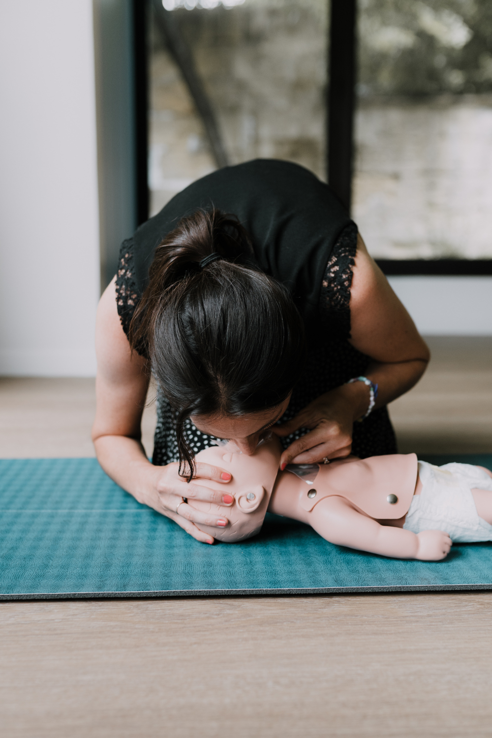 Formation aux gestes de premiers secours pédiatriques : une formatrice pratique la ventilation artificielle sur un mannequin de bébé lors d’un atelier.