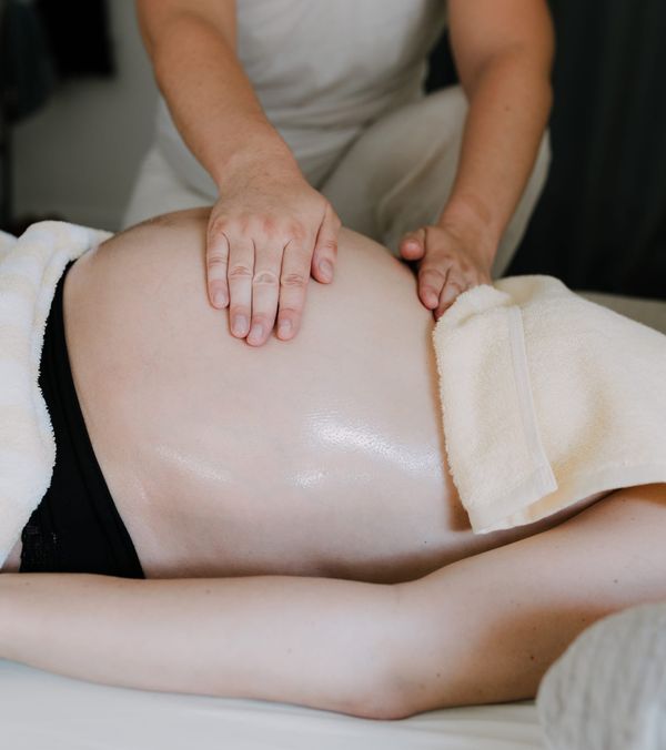 Massage prénatal sur le ventre d'une femme enceinte allongée, moment de bien-être et de détente