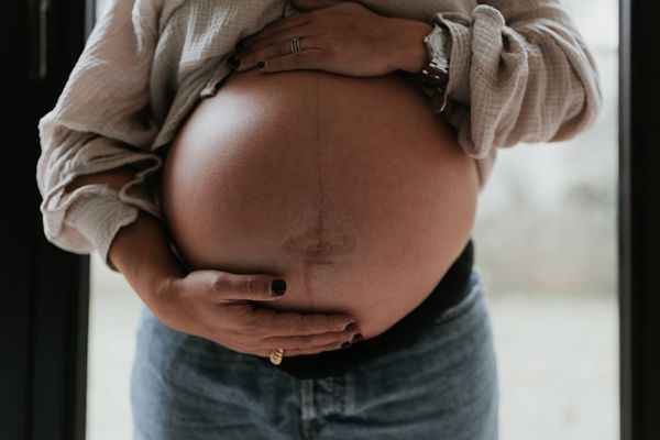 Ventre arrondi d’une femme enceinte avec ses mains posées dessus, symbole de grossesse et de maternité