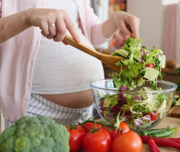 Femme enceinte préparant une salade de légumes frais – alimentation saine pendant la grossesse