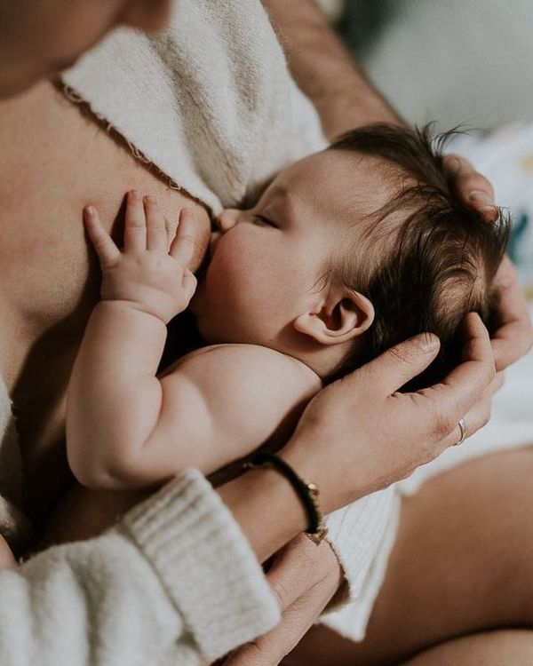 Bébé allaité tendrement dans les bras de sa maman, en contact peau à peau, moment doux et apaisant d’allaitement.