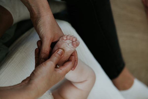 Massage des pieds d’un nourrisson par un adulte, moment de douceur favorisant le lien parent-bébé et la détente du nouveau-né.