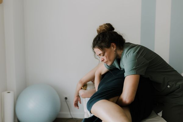 Ostéopathe réalisant une consultation post-partum sur une jeune maman dans un cabinet lumineux, accompagnement après accouchement chez Yada.