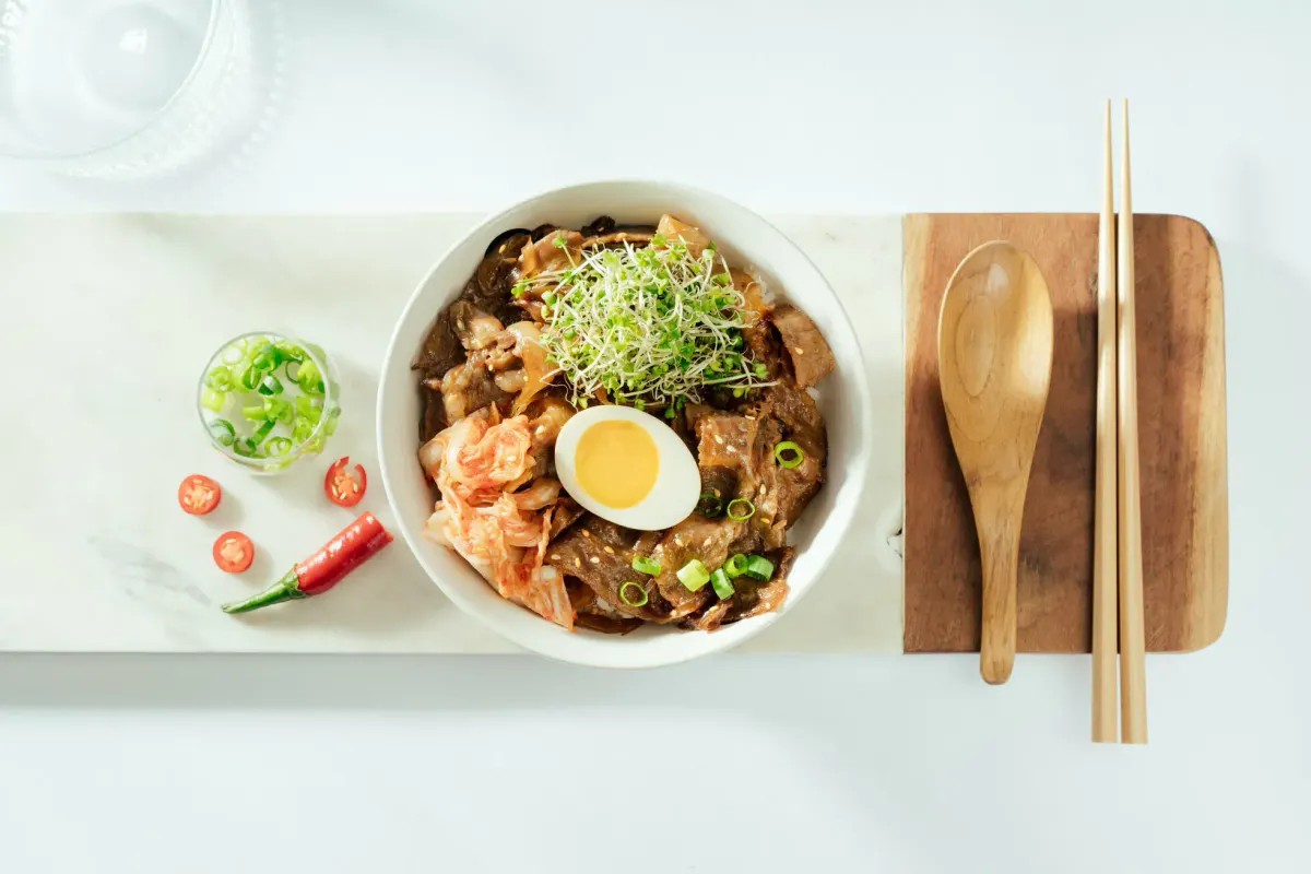 白色餐桌上的肉片飯、泡菜、水煮蛋與芽苗