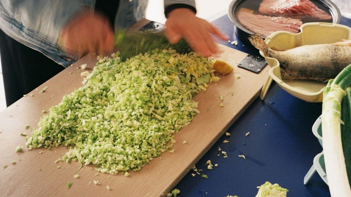 砧板上切得細碎的十字花科蔬菜，旁邊放著魚與蔥
