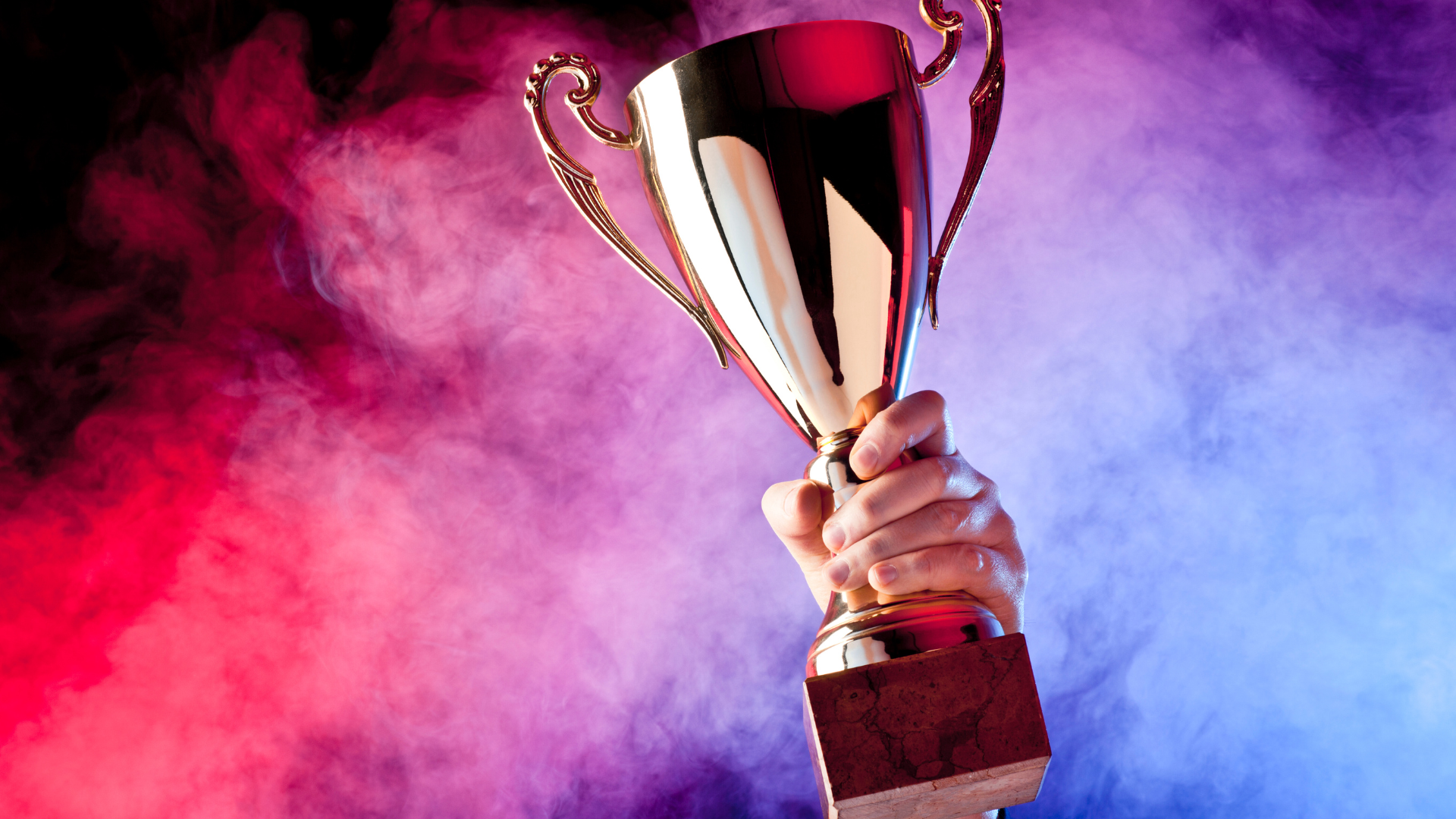 a big trophy, held against a blue and red smokey background